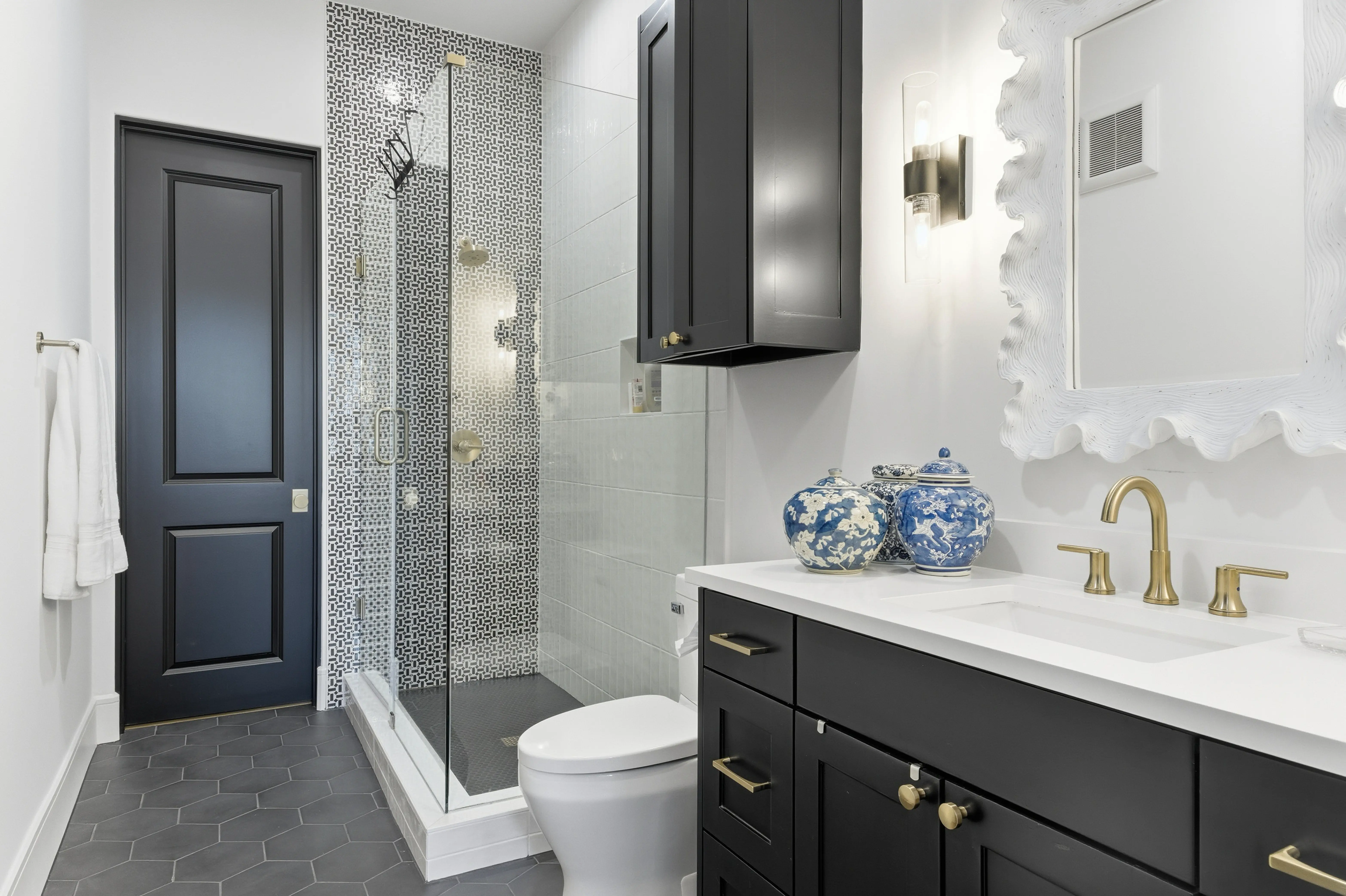 Guest bathroom with patterned tile shower and dark cabinetry