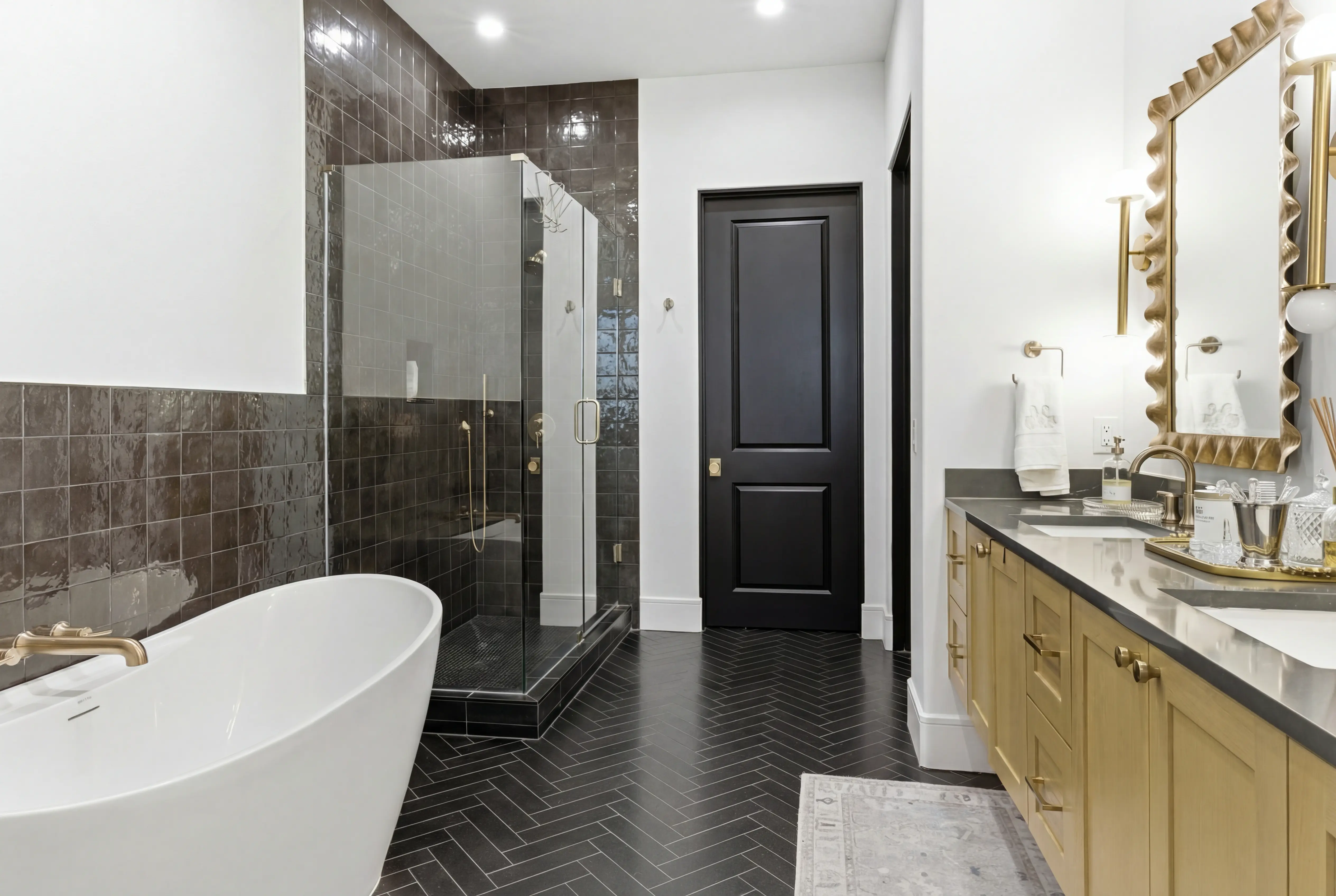 Primary bathroom with freestanding tub, herringbone tile, and glass shower